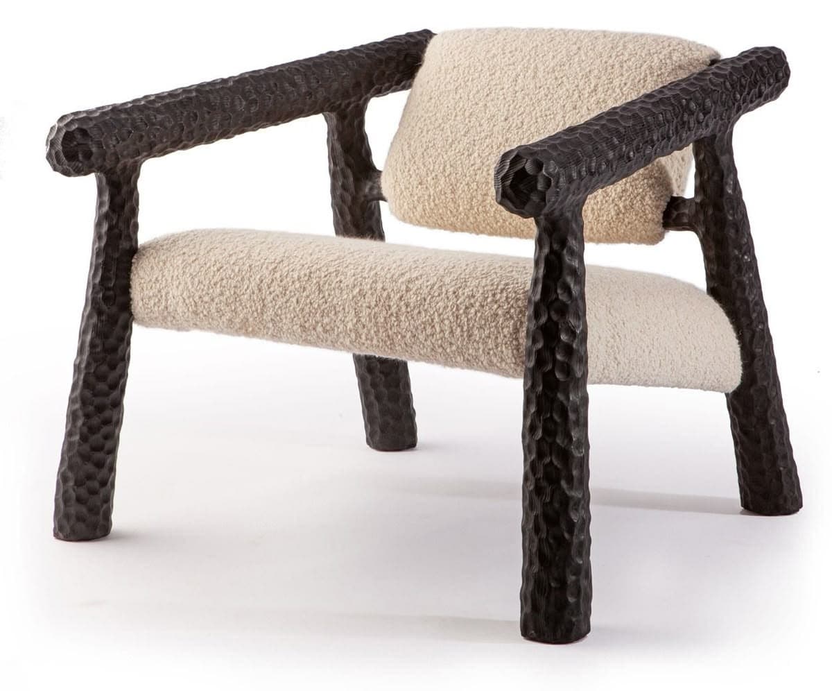 An armchair with a distinctive sculpted frame and upholstered seating and backrest. The frame elements appear to be made of a dark, textured material, possibly metal or a composite, with a hammered or carved finish. The seat and backrest are covered in a textured, boucle-like fabric in a light, neutral color. — 3D model