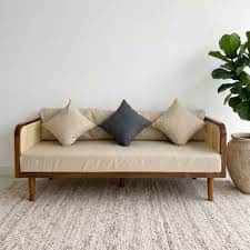 A modern daybed featuring a natural wood frame with cane webbing panels, a thick upholstered seat cu… — 3D model