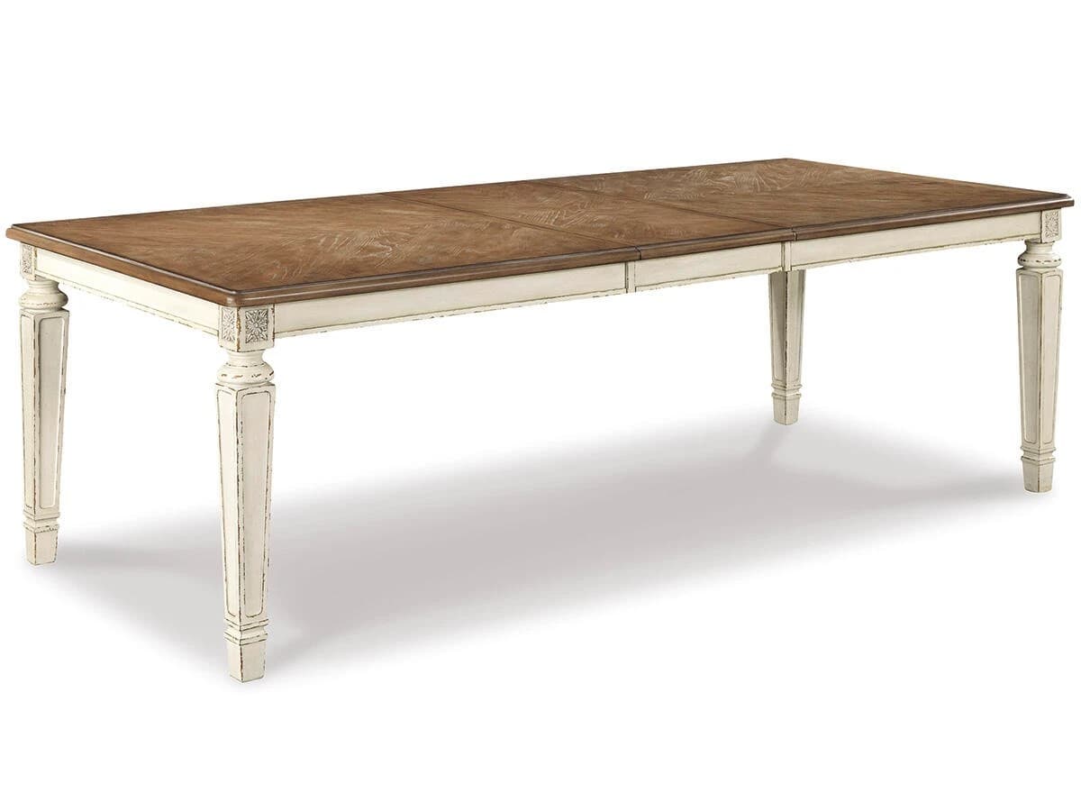 A rectangular dining table with a two-tone finish. The tabletop features a wood grain pattern with a medium brown stain, and it appears to have extension leaves. The table legs and apron are painted a distressed cream or off-white color. The legs are fluted and have decorative carvings near the top, above the apron. — 3D model