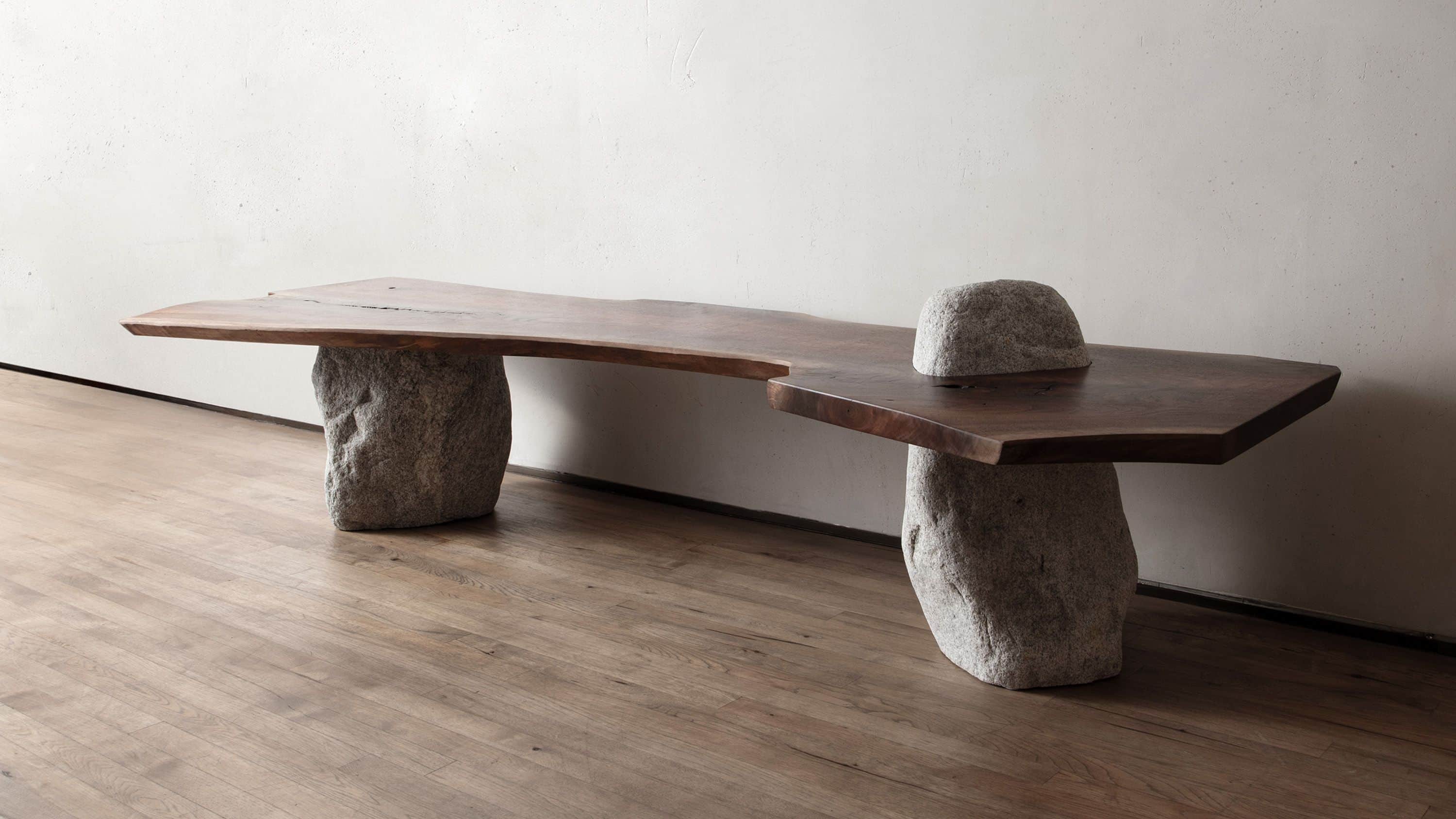 A unique bench featuring a live-edge wooden slab top supported by two irregular, natural stone bases… — 3D model