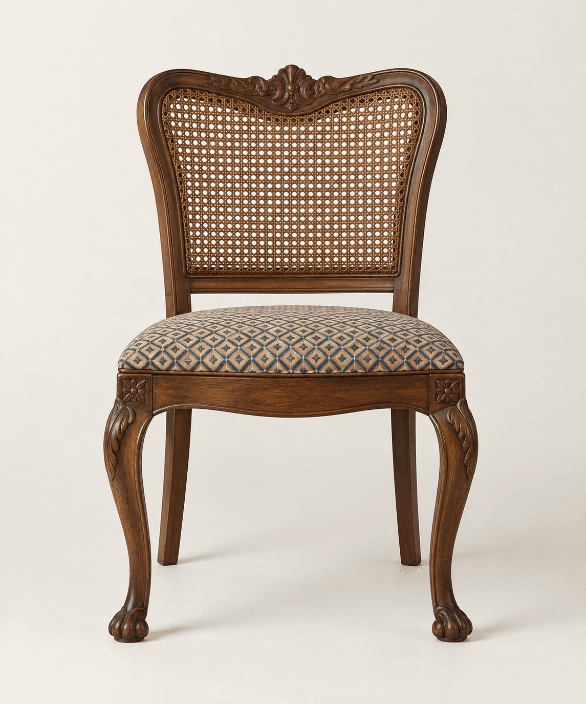 A traditional dining chair with a dark wood frame, featuring a woven cane backrest and an upholstered seat with a geometric pattern. The chair exhibits ornate carvings on its curved back, apron, and cabriole legs, which terminate in stylized claw feet. — 3D model