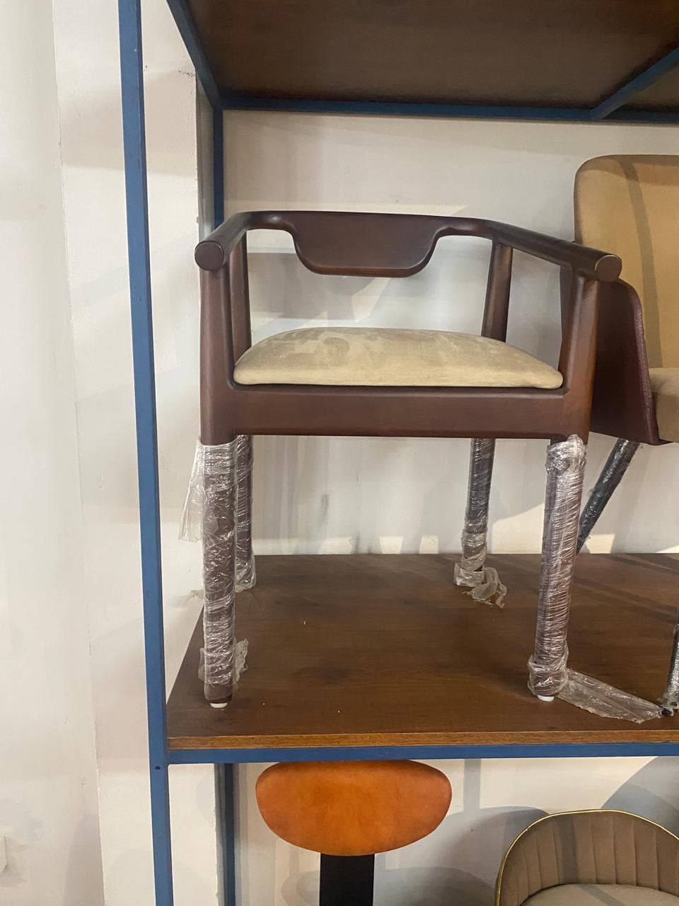 A contemporary armchair featuring a dark stained wooden frame and a light beige upholstered seat. It has a distinctive curved wooden backrest and armrest structure. — 3D model