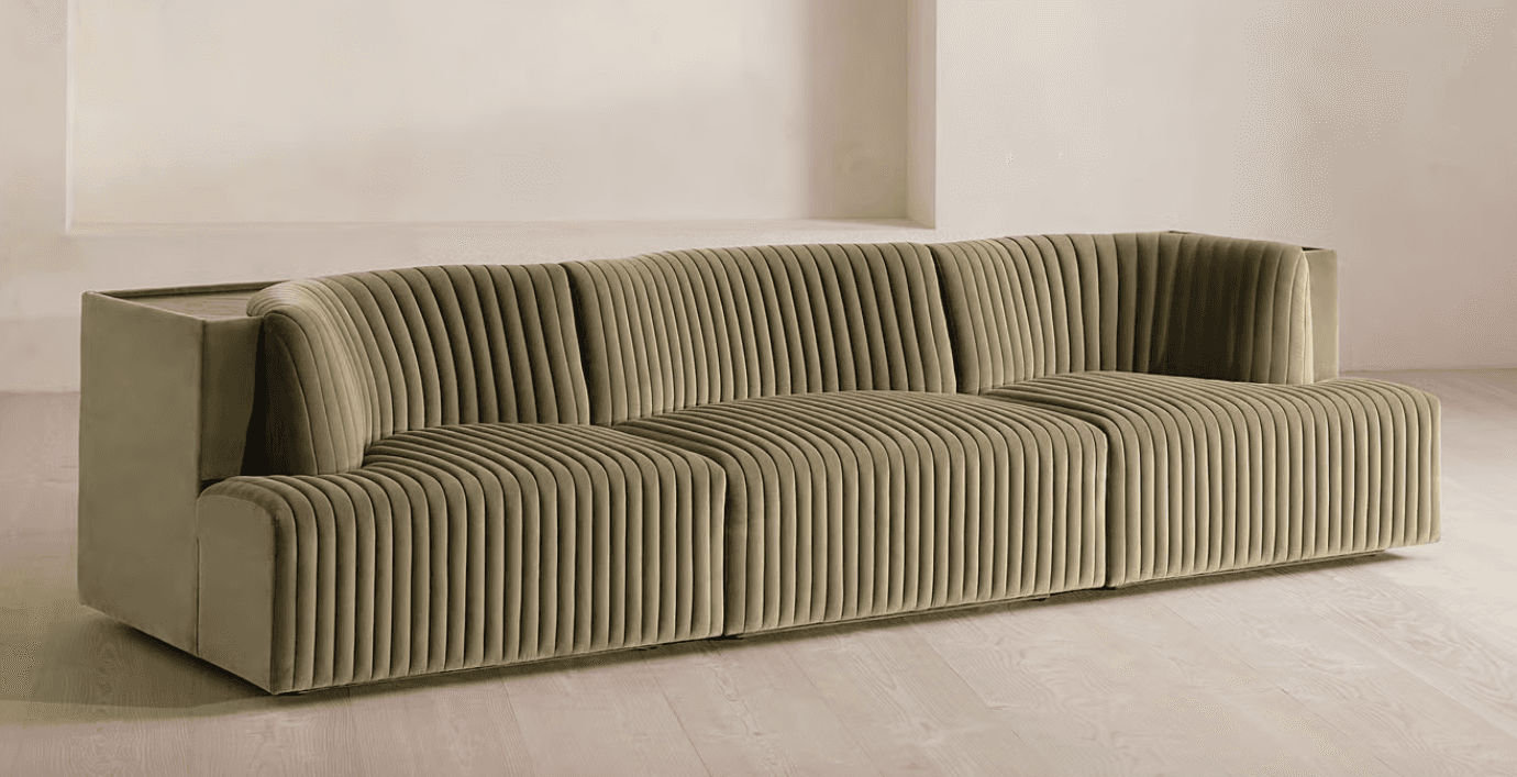 A long, contemporary sofa with a channeled upholstery design. The sofa features a modular appearance… — free GLTF 3D model