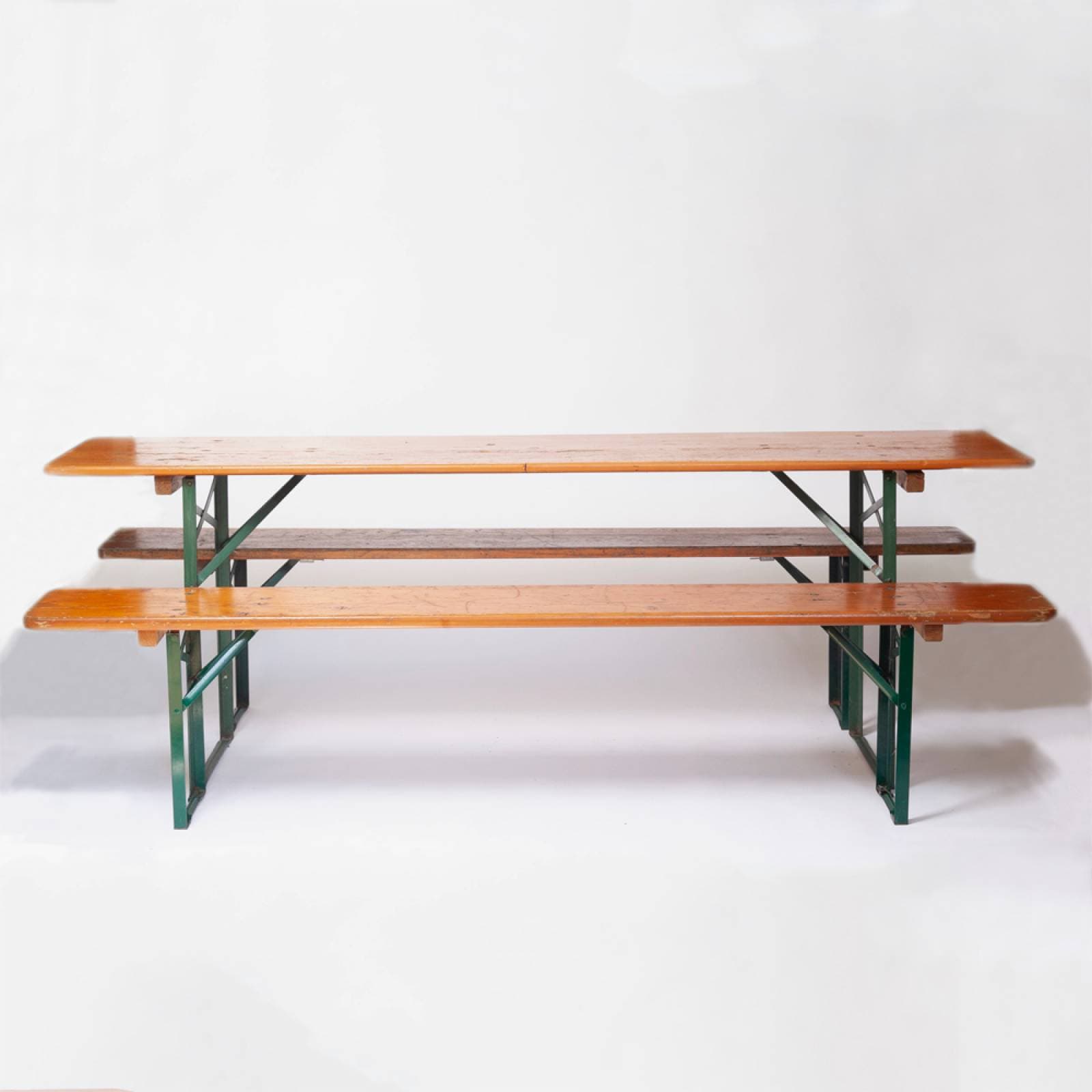 A set comprising one long rectangular table and two matching benches, all constructed with light-colored wooden tops and dark green painted folding metal legs. The design is robust and utilitarian, typical of outdoor or event furniture, showing signs of use. — 3D model