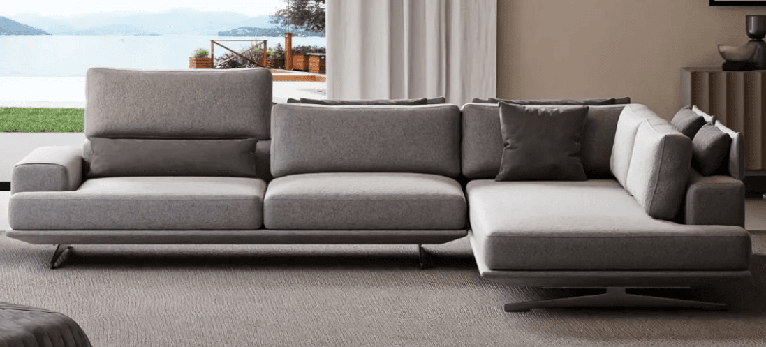A modern, sectional sofa with a light grey fabric upholstery and dark grey accent pillows. The sofa features a low-profile design with thin, angled metal legs, and adjustable headrests on some sections. It is configured in an L-shape. — 3D model