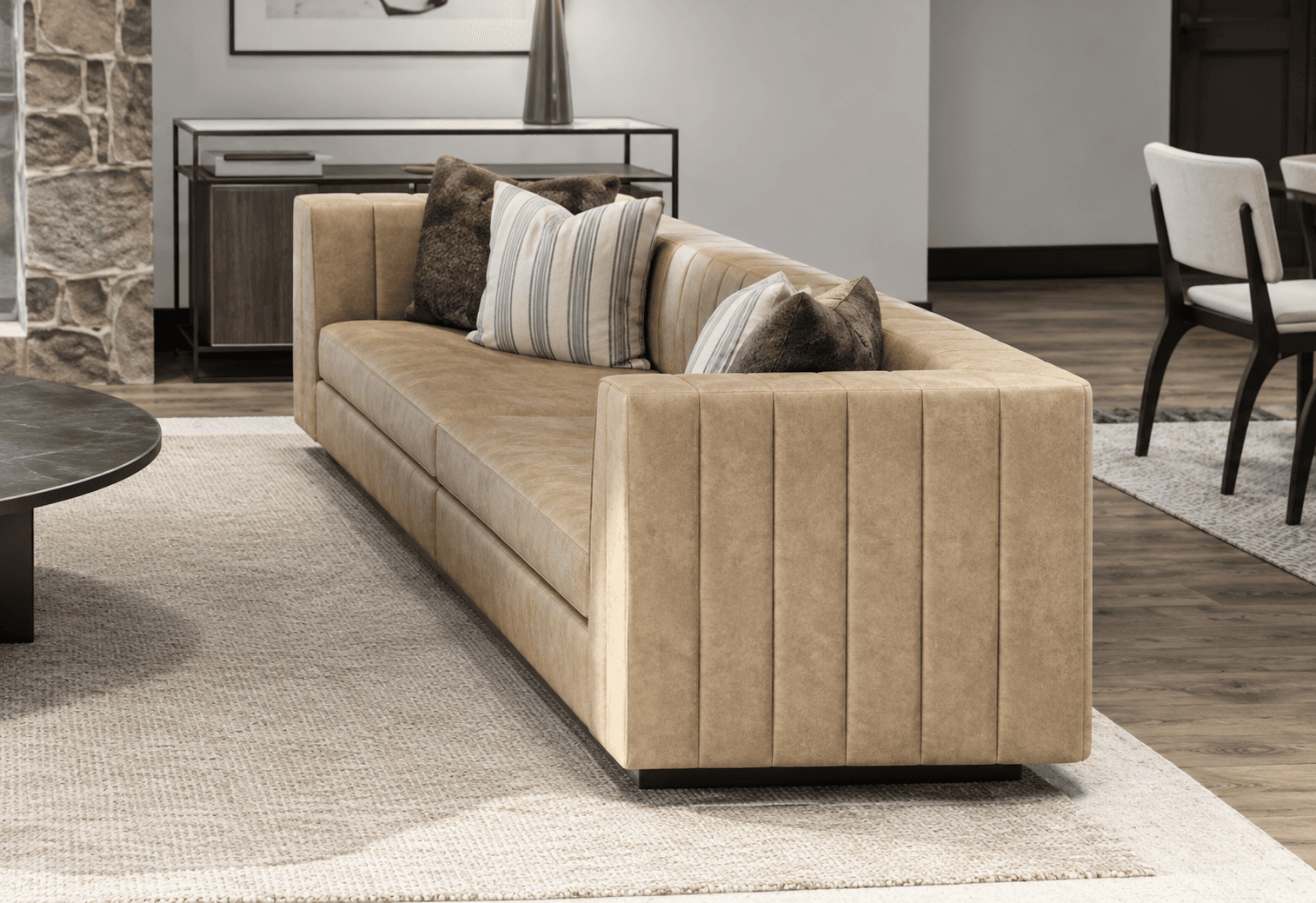 A modern, rectilinear sofa upholstered in a light tan material, featuring distinct vertical channel tufting on the exterior arm and back panels, and resting on a recessed dark base. — 3D model