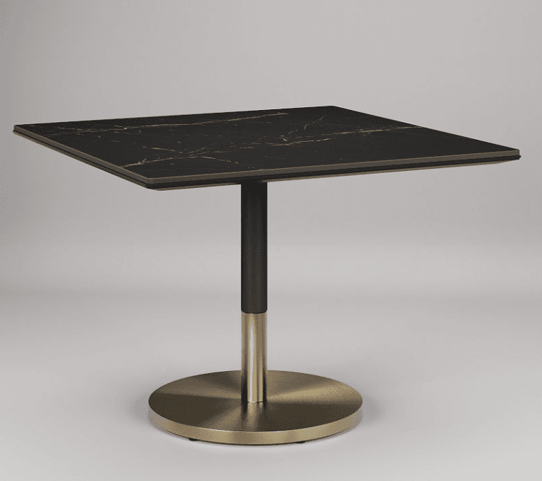 A square-topped table with a dark, marble-patterned surface and a single pedestal base. The base consists of a matte black cylindrical column transitioning to a brushed brass cylindrical section, all supported by a circular brushed brass base. — 3D model
