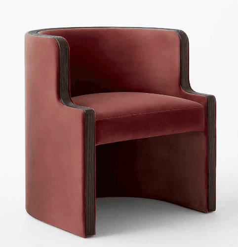A contemporary barrel-back accent chair upholstered in deep red velvet, featuring a continuous curved back and armrests with prominent dark wood trim along the exterior edges. The chair has a low profile and a fully upholstered base. — 3D model