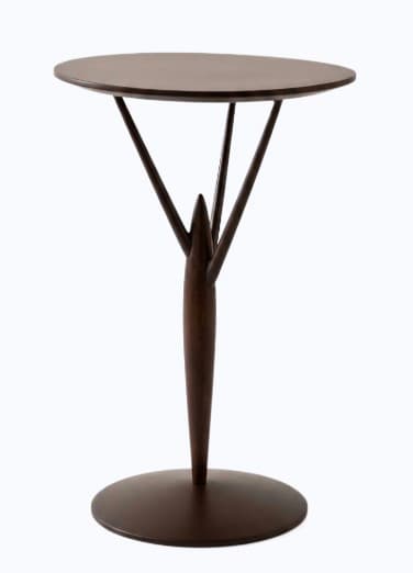 A contemporary pedestal accent table featuring a circular tabletop and base, supported by a distinctive, sculptural central column. The column tapers towards the bottom and branches into three slender struts that support the tabletop, creating an elegant, tree-like silhouette. The entire piece is rendered in a uniform dark brown or espresso matte finish. — 3D model