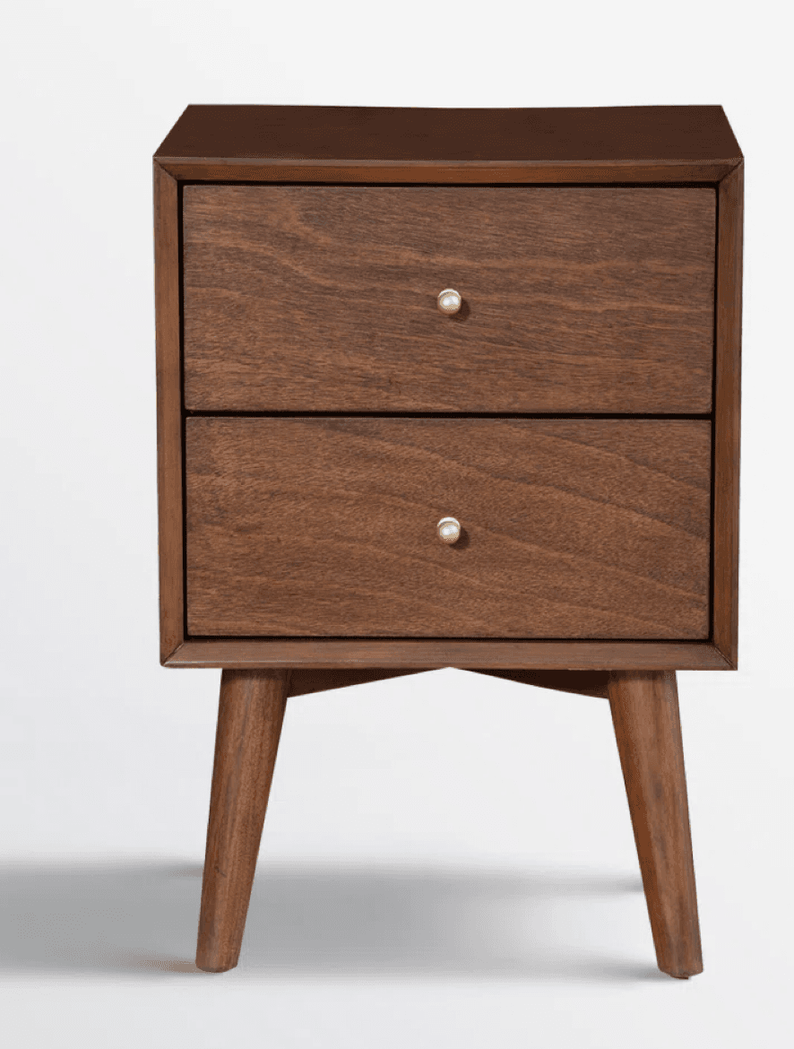 A mid-century modern-style nightstand with a dark wood finish. It features two drawers, each with a small, round, brass-toned knob. The unit is supported by four tapered legs that angle outwards. — 3D model
