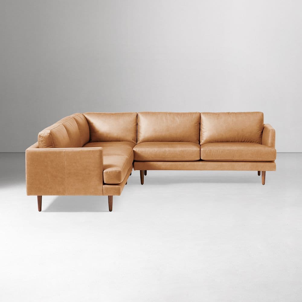 An L-shaped sectional sofa upholstered in tan leather, featuring a modern low-profile design with square arms and tapered wooden legs. The sofa consists of two main components joined at a right angle. — 3D model