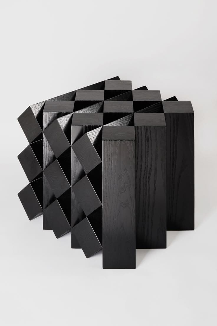 A contemporary black cabinet with a striking geometric design. The front facade is composed of an arrangement of cubes and prisms that create a dynamic, three-dimensional effect, reminiscent of a tessellation or a fragmented pattern. The primary structure appears to be made of wood with a dark, possibly stained or painted finish, showcasing a visible grain texture. The piece has a modern, abstract aesthetic, suggesting it could function as a statement piece of furniture for storage or display. — 3D model