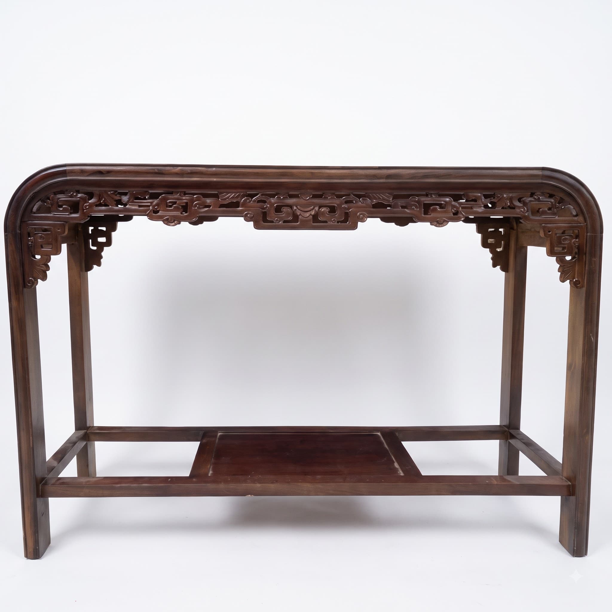 A long, narrow dark brown wooden console table featuring a rectangular top with gently curved ends and an intricately carved apron. It is supported by four straight legs and includes a lower recessed shelf. — 3D model