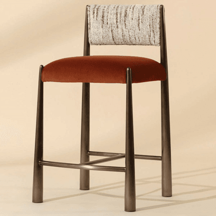A contemporary bar stool featuring a dark bronze-toned metal frame with tapered legs and integrated footrests. The seat is upholstered in a rich burnt orange velvet, while the rectangular backrest is covered in a light, textured cream and brown fabric. The design is sleek and modern. — 3D model
