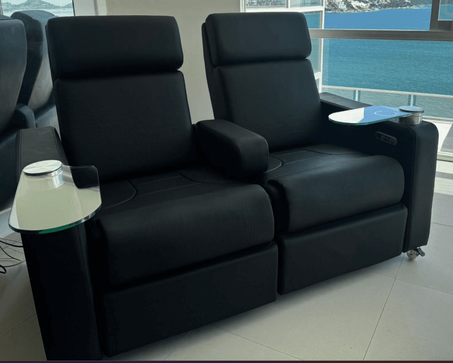 A two-seat black upholstered reclining loveseat designed for home theater environments, featuring individual power recline, integrated cup holders, and removable frosted glass swivel trays. — 3D model