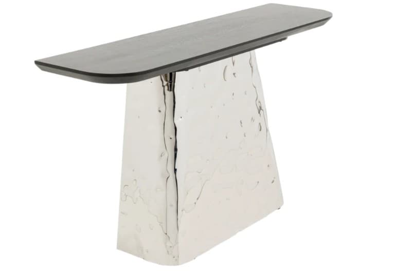A modern console table featuring a dark, elongated rectangular top with gently rounded edges, supported by a substantial, polished hammered metal base. The base has a distinctive, irregular, and textured surface, giving it a unique sculptural quality. Its form tapers slightly, widening towards the bottom for enhanced stability and visual presence. — 3D model