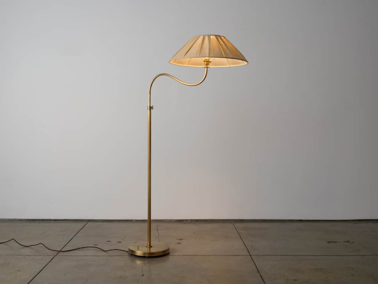 A brass-finished swing-arm floor lamp featuring a circular base, a slender vertical stem, and an art… — 3D model