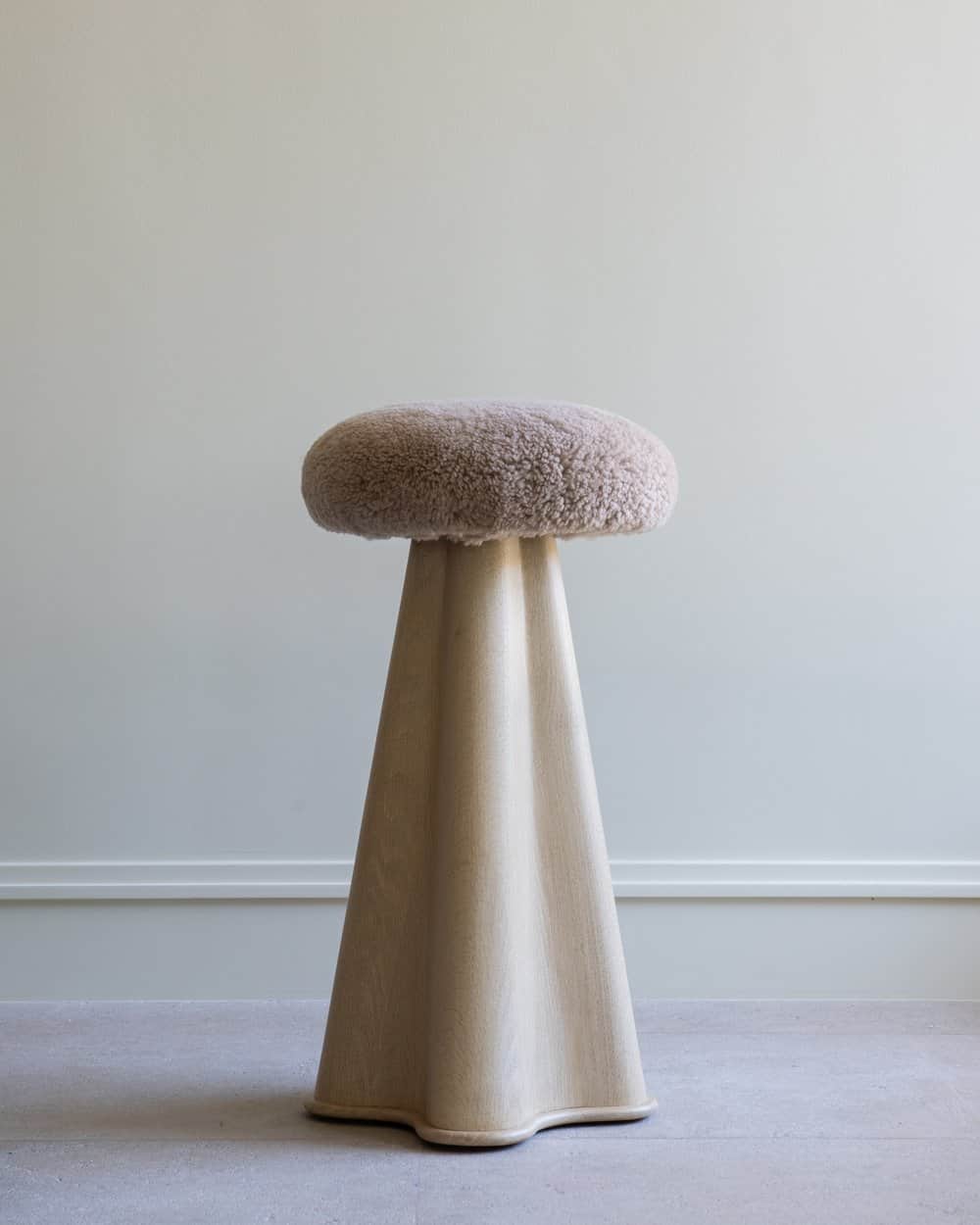 A tall, modern pedestal stool featuring a round, fluffy boucle upholstered seat in a light beige col… — 3D model