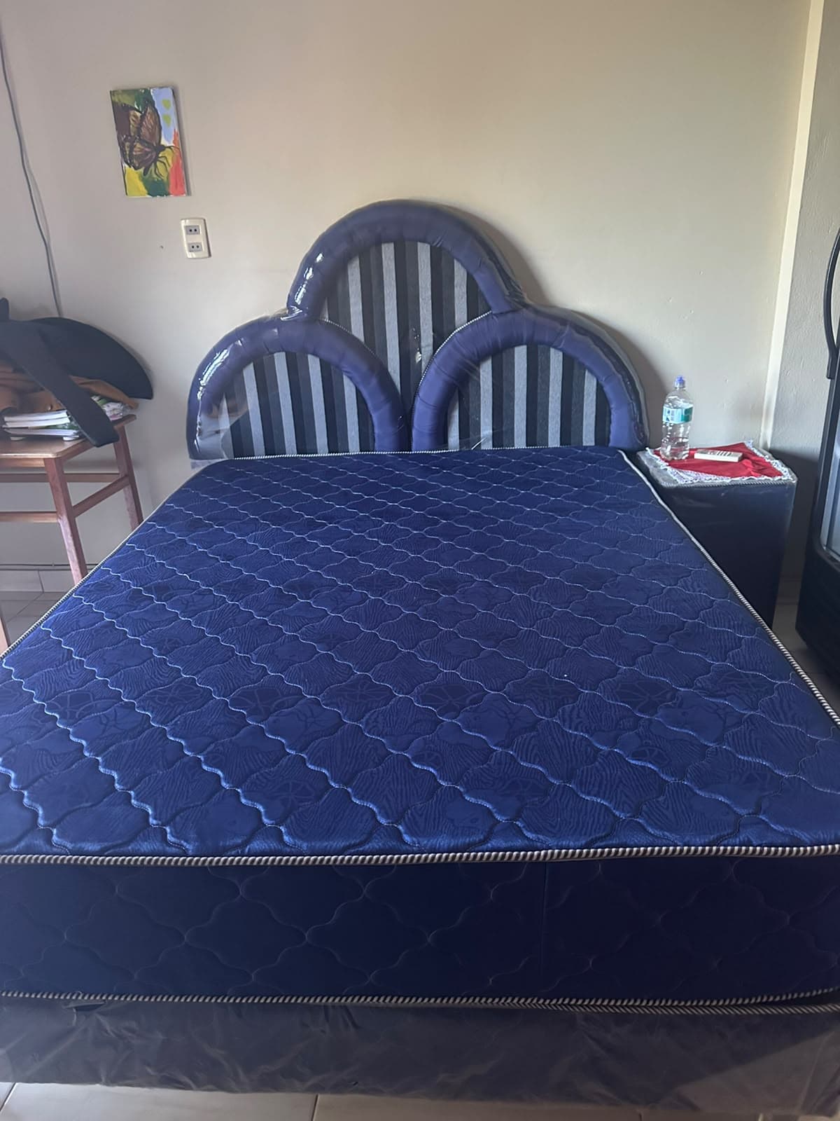 An upholstered platform bed featuring a distinctive triple-scalloped headboard. The headboard combines solid navy blue fabric with vertical grey and white stripes. The platform base is upholstered in matching navy blue fabric, and the bed includes a navy blue diamond-quilted mattress with white piping. — 3D model