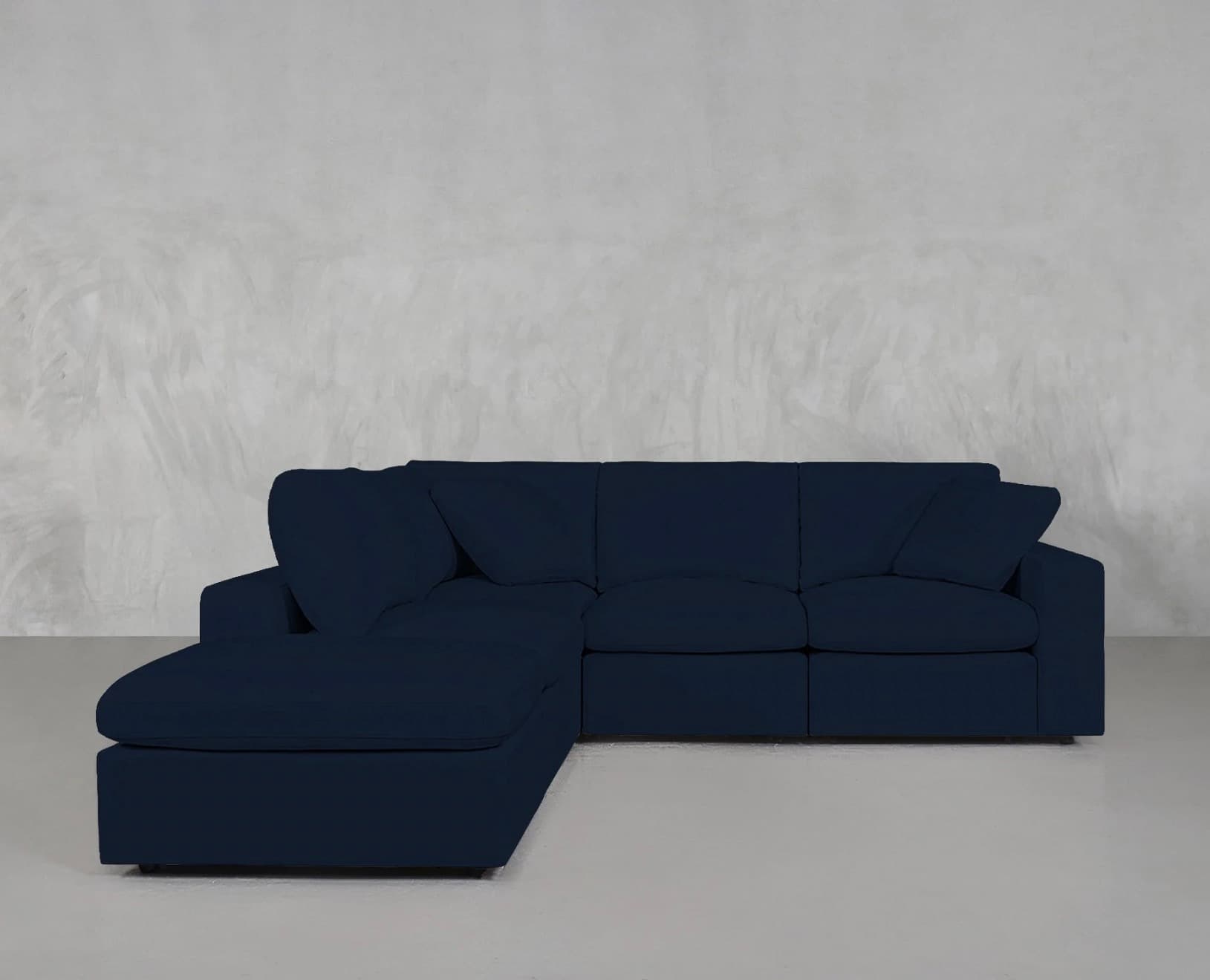 An L-shaped modular sectional sofa upholstered in a dark blue fabric. It features a chaise lounge component on one end, deep seating, plush back cushions, and includes several matching throw pillows. The design is contemporary, emphasizing comfort and versatility, suitable for various living spaces. — 3D model