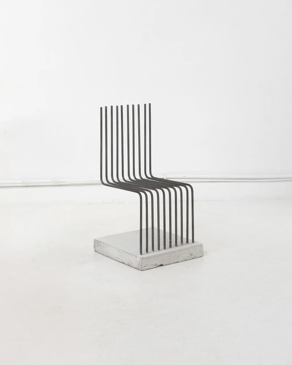 A contemporary chair constructed from multiple parallel steel rods forming the seat and backrest, anchored to a solid concrete base. The steel rods are bent to create the seating and back support. The overall design is minimalist and industrial. — 3D model