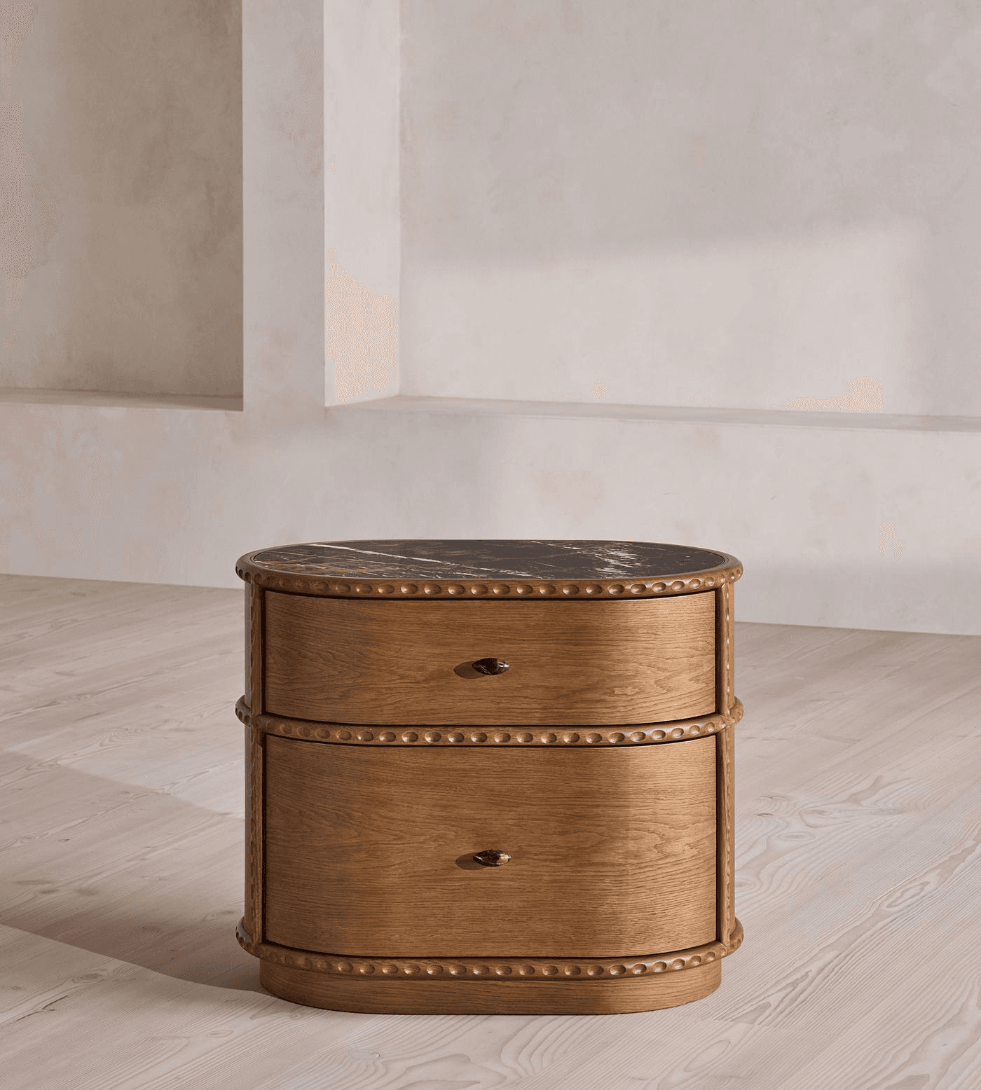 A small, oval-shaped wooden nightstand featuring two drawers and a black marble top with white veining. It has decorative beaded trim along the edges and between the drawers. — 3D model