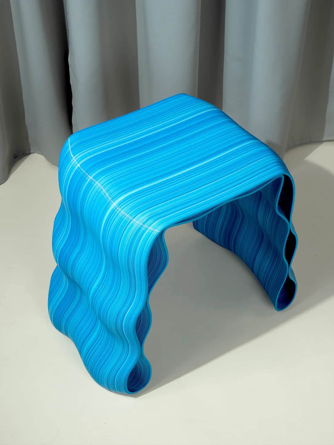 A contemporary stool with a fluid, wave-like design. The structure is composed of numerous thin, lay… — 3D model