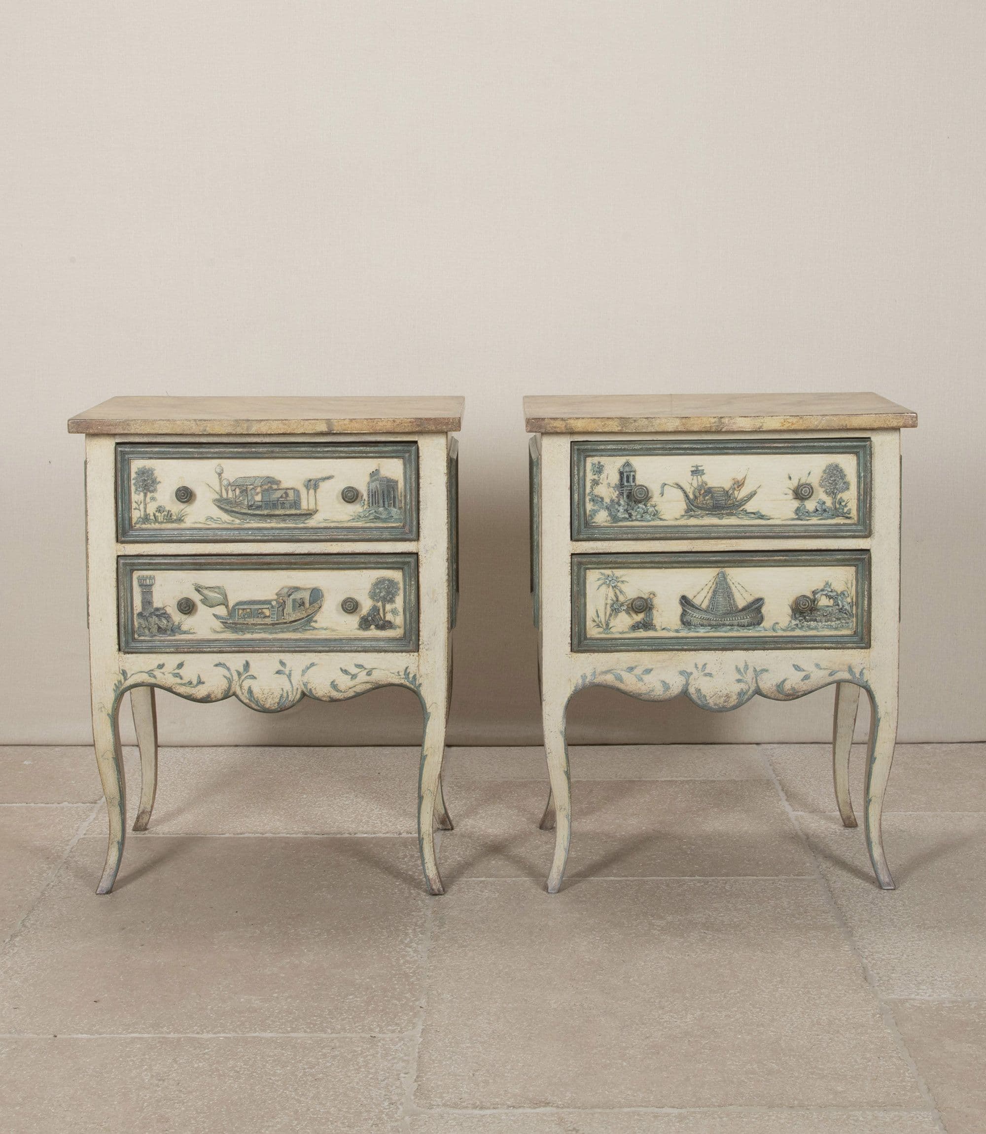 A pair of matching nightstands with two drawers each. The front panels of the drawers and the lower skirt are adorned with hand-painted blue and white scenic details, featuring boats and architectural elements. The nightstands have a distressed cream-colored finish and are supported by four cabriole legs. The top surface appears to be a different material, possibly a veneer or stone. — 3D model