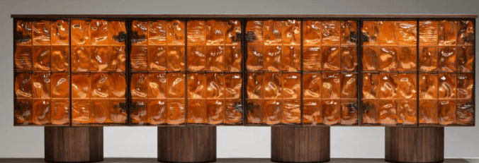 A long, low cabinet with a dark wood frame. The front features multiple panels of textured, amber-colored glass, arranged in a grid pattern. The cabinet is supported by four cylindrical wooden bases. — 3D model