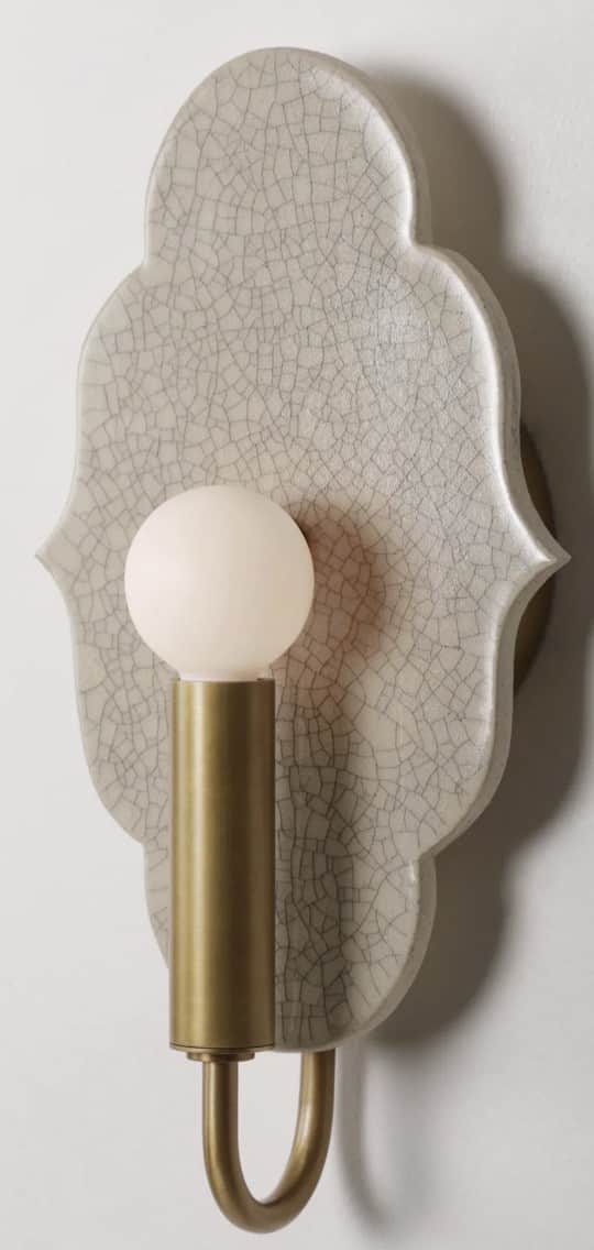 A wall-mounted light fixture featuring a decorative quatrefoil-shaped ceramic backplate with a crack… — 3D model