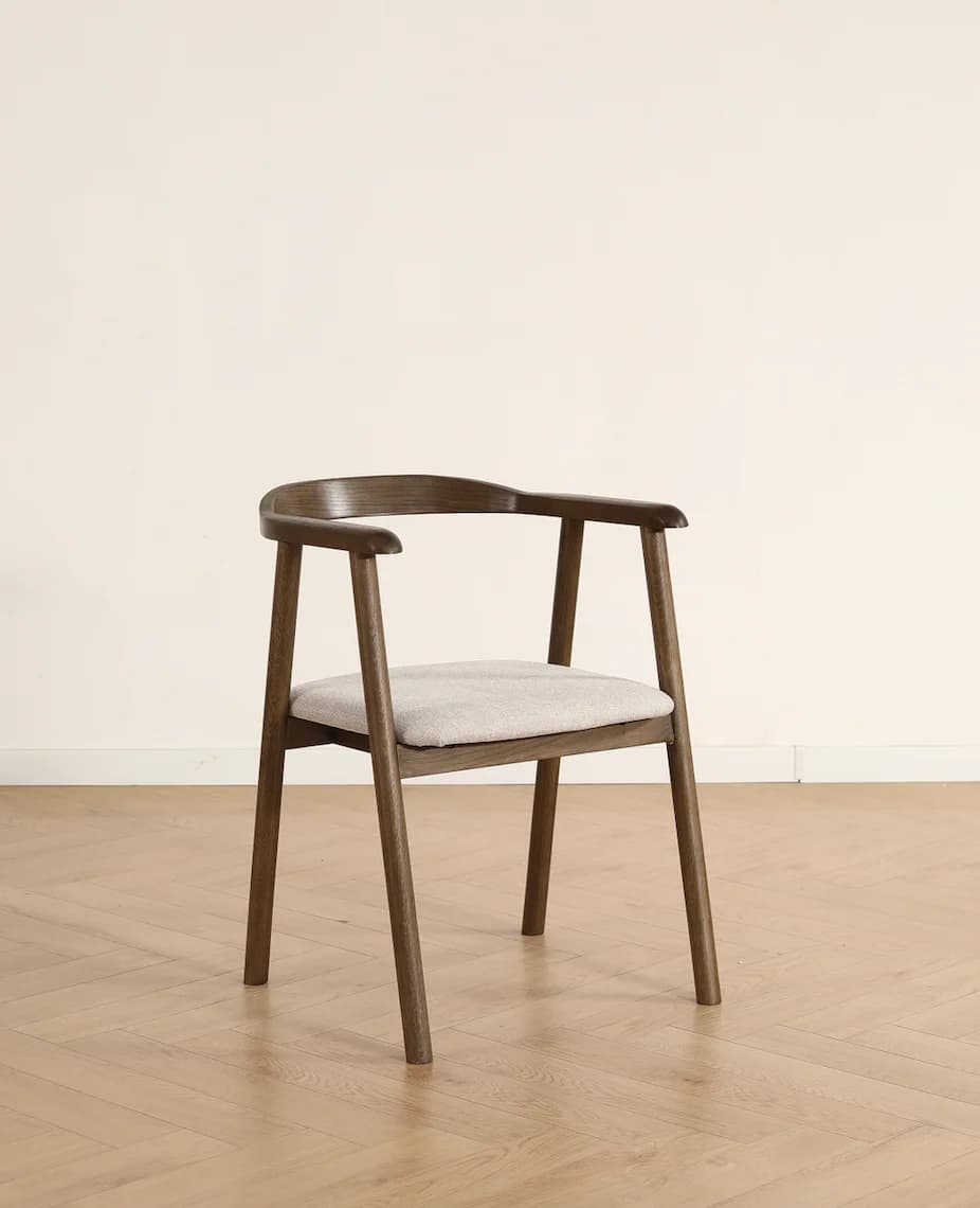 A modern dining armchair crafted from dark wood with a curved backrest and integrated armrests, featuring a light beige upholstered seat cushion. — 3D model