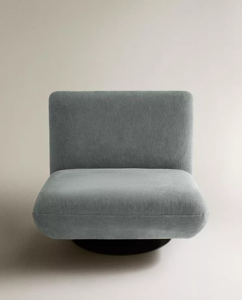 An armless upholstered lounge chair featuring a low-profile, minimalist design with a concealed swivel base. The chair is fully upholstered in a light grey-blue textured fabric, presenting a modern aesthetic. — 3D model
