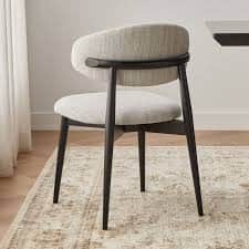 A modern dining chair featuring a light-colored upholstered seat and a curved backrest, supported by… — 3D model