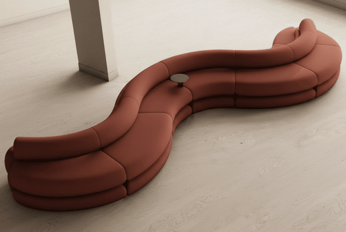 A modular, serpentine sofa with a distinctly organic, flowing shape. It appears to be constructed from multiple individual seating modules that seamlessly connect to form a continuous, curved seating arrangement. The sofa is upholstered in a matte, reddish-brown material and features rounded edges and a low profile. A small, circular, dark-colored table is integrated into the curve of the sofa near its center. — 3D model