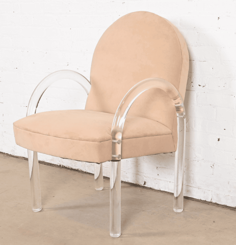 A contemporary armchair with a rounded back and upholstered seat and backrest. The chair features curved armrests and legs constructed from clear acrylic material. The upholstery appears to be a soft, textured fabric. The frame is supported by four cylindrical acrylic legs. — 3D model