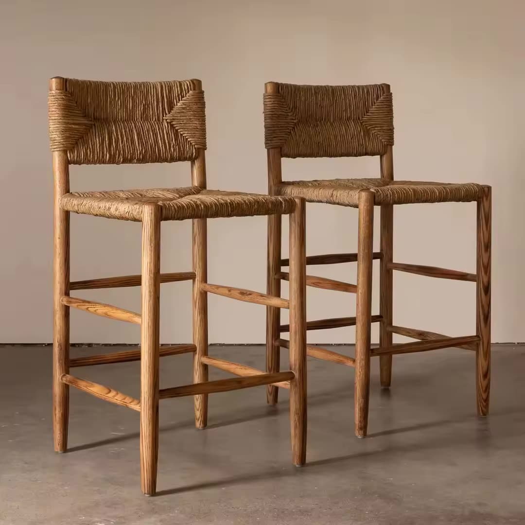 A natural wood bar stool featuring a woven rope seat and backrest, supported by four tapered wooden legs connected by horizontal and diagonal footrests. The construction appears sturdy and the materials suggest a natural, organic aesthetic. — 3D model