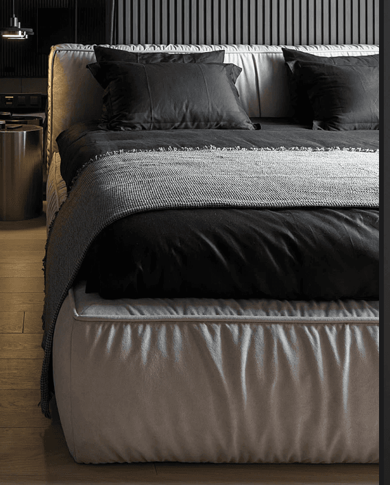 A modern upholstered platform bed featuring a low-profile base and a tall, pleated headboard. The bed is covered in a light beige or off-white fabric, with a distinctive vertical pleated texture on both the headboard and the perimeter of the bed base. It is dressed with black bedding and a grey knitted throw blanket. — 3D model