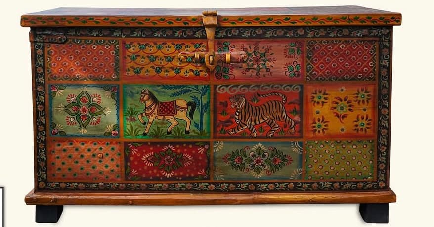 A rectangular wooden chest featuring an elaborate hand-painted design across its top and front surfaces. The painting consists of multiple square and rectangular panels, each with distinct colorful motifs including animals like tigers and horses, as well as floral and geometric patterns, arranged in a mosaic-like fashion. The side panels are left in a natural wood finish. The chest is equipped with a brass-toned latch on the front and sits on short, dark-colored feet. — 3D model