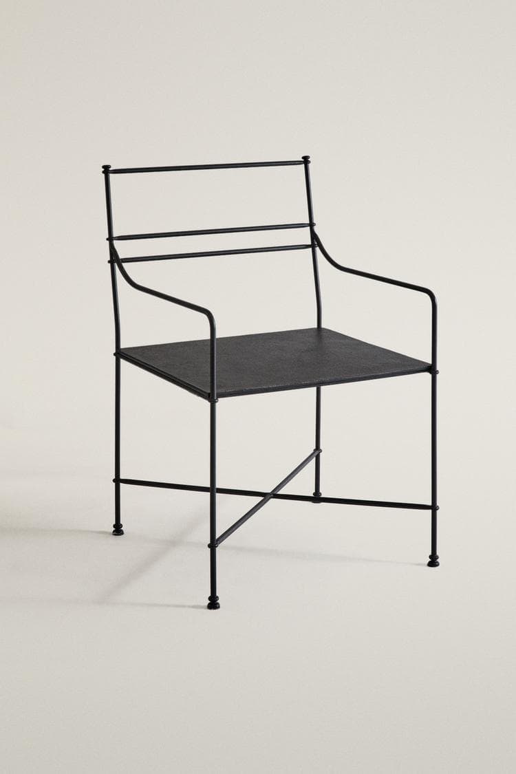 A minimalist black armchair constructed from thin tubular metal. It features a flat, rectangular seat and a backrest composed of two horizontal metal bars. Integrated armrests curve gently from the backrest to the front of the seat. The four legs are reinforced with an X-shaped stretcher detail near the floor. The entire piece has a matte black finish, suggesting a powder-coated steel or similar metal. — 3D model