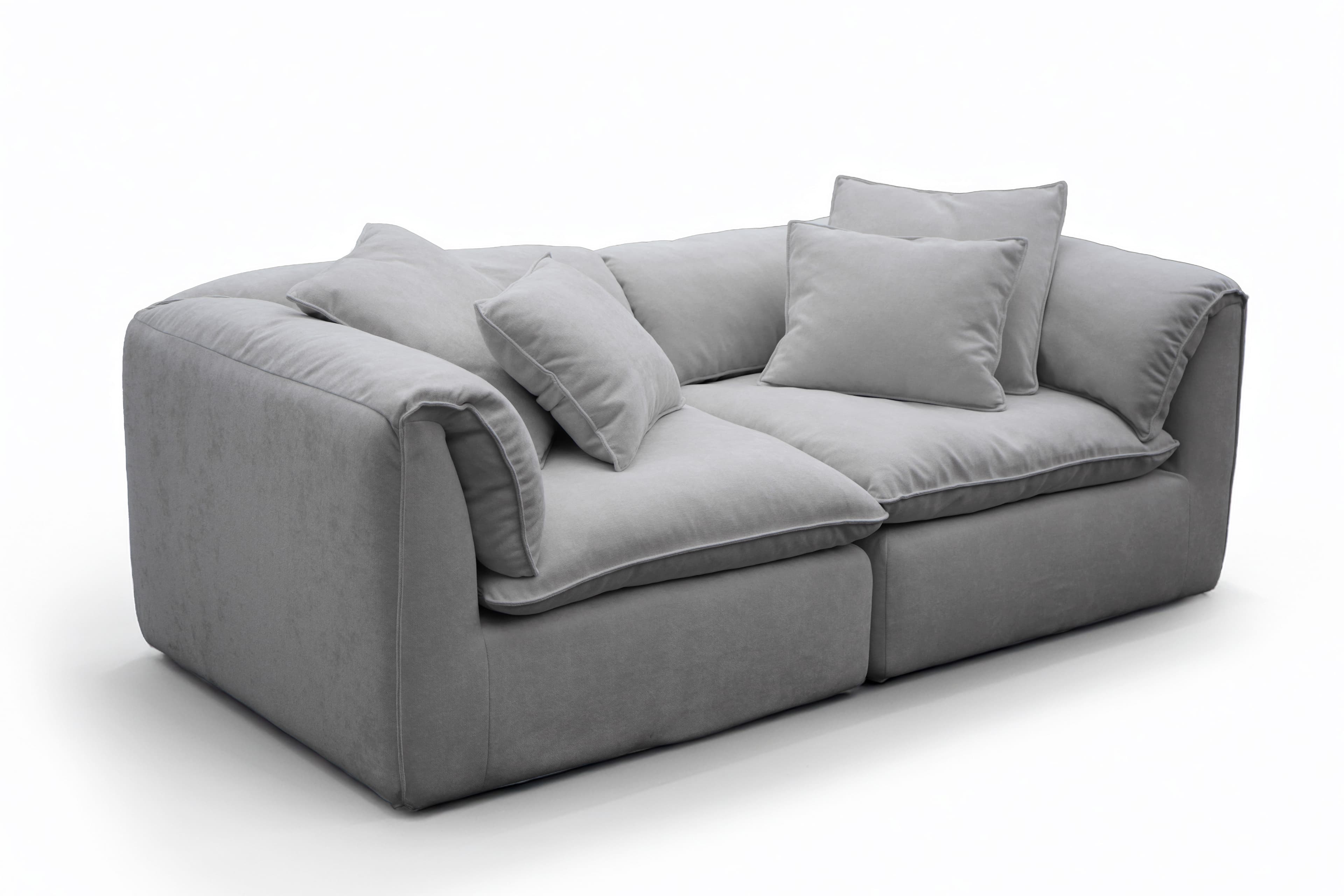 A contemporary, light gray two-seater sofa featuring a plush and inviting design. It consists of two main upholstered sections, providing generous seating. The sofa has thick, soft cushions for both the seat and back, along with several matching throw pillows, all upholstered in a uniform light gray fabric with subtle piping detail. The armrests are wide and softly padded, integrated into the overall plush aesthetic. The piece appears designed for maximum comfort and relaxation, with a low profile and a substantial, inviting presence. — 3D model