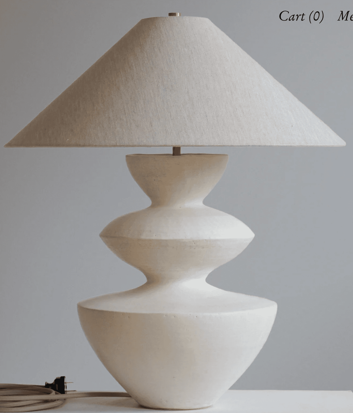 A modern sculptural table lamp featuring an off-white conical fabric shade atop a similarly colored, tiered ceramic base. The base has an organic, curvilinear form, consisting of three distinct sections that narrow and widen, creating a stacked, fluid silhouette. A small brass accent is visible at the very top, connecting the shade to the lamp's body. The overall aesthetic is minimalist and contemporary, emphasizing form and texture. — 3D model