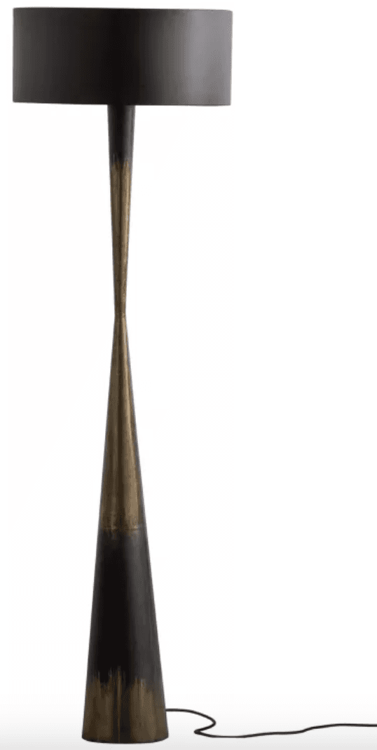 A tall, slender floor lamp featuring a sculptural, tapered metal base with a distinctive two-tone patinated finish. The base transitions from a darker hue at the bottom to an aged bronze or brass tone in the middle, then back to dark near the top. It is topped with a simple, cylindrical black drum shade. — 3D model