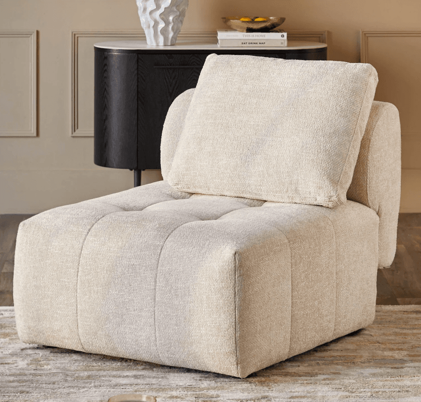 A light beige, upholstered, modular armless chair section with a separate back cushion, featuring button-tufted details on the seat and backrest. — 3D model