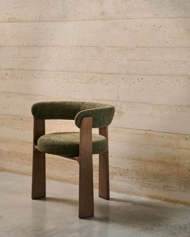 An upholstered dining armchair featuring a curved backrest and integrated armrests, supported by a s… — 3D model