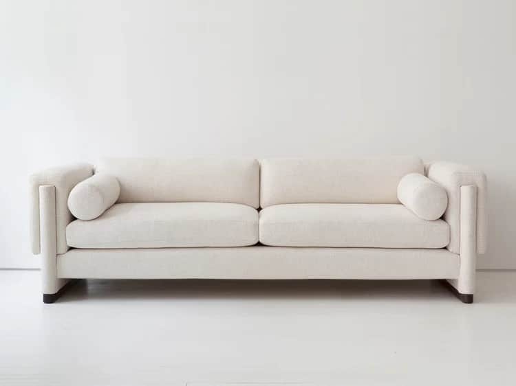 A modern, upholstered sofa with a rectangular frame and distinct cylindrical armrests. The sofa feat… — 3D model