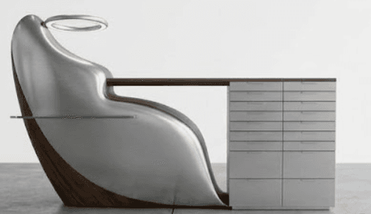 A highly modern and sculptural desk unit featuring an integrated ergonomic chair, a work surface, and a multi-drawer storage cabinet. The design combines a curved, polished metal shell with dark wood accents and a glass side shelf. An illuminated ring fixture is positioned above the chair. — 3D model