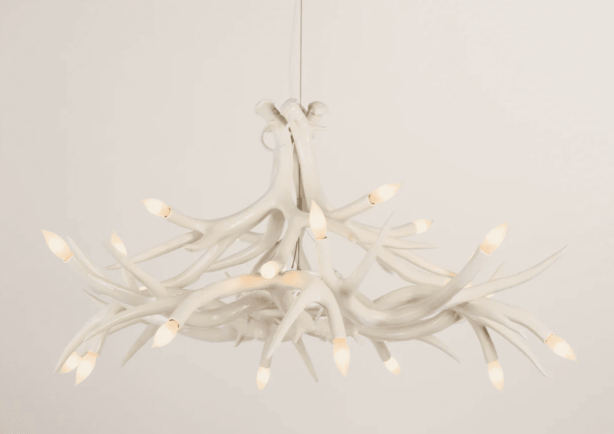 A white chandelier designed to resemble a cluster of antlers. It features multiple branching elements that curve and intertwine, with small, flame-shaped bulbs positioned at the ends of many of these branches, providing illumination. The overall form mimics natural antler growth patterns, creating a rustic yet sophisticated aesthetic. — 3D model