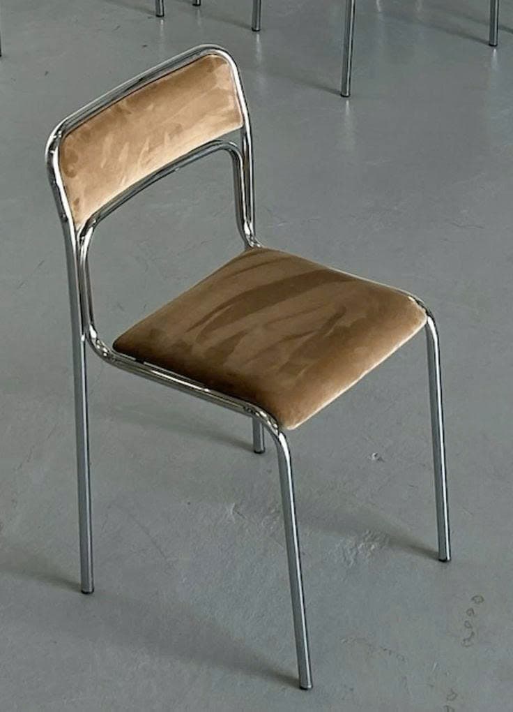 A modern dining chair featuring a sleek, polished chrome-plated tubular steel frame and upholstered seat and backrest in a neutral tan velvet or velour fabric. The chair has an armless design with a continuous frame forming the back support and legs. — 3D model