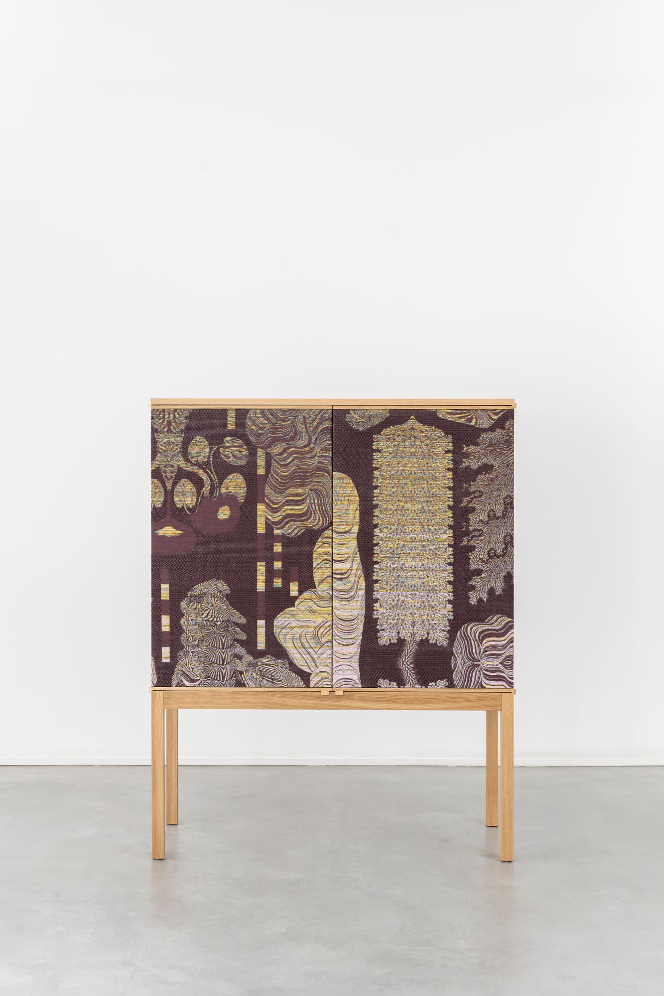 A tall, rectangular wooden cabinet featuring two doors adorned with a richly patterned, multi-colored design. The cabinet is constructed from light-toned wood, visible on its top, sides, and the four straight legs that elevate it from the floor. The intricate pattern on the doors displays abstract, organic shapes in shades of dark red, gold, cream, and brown, creating a striking contrast with the minimalist wooden frame. It appears to be a modern piece designed for storage. — 3D model