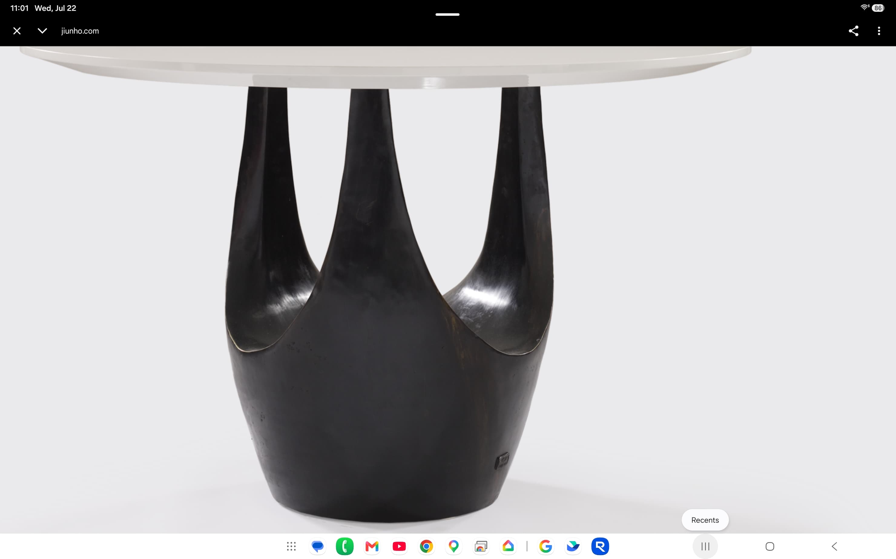 A contemporary dining table featuring a round white tabletop supported by a distinctive dark, sculptural pedestal base with multiple organic lobes. — 3D model